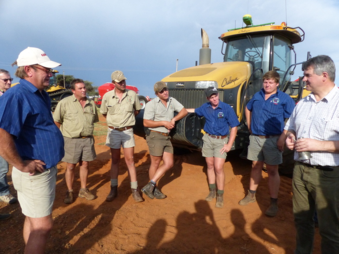 Le patron de l'exploitation en chemise bleu, accompagné de ses employés et de Mickaël Horsch à droite pose devant le matériel de la ferme de 15 000 ha en monoculture de maïs grains